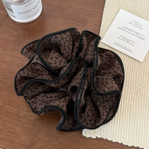 Gros plan d'un chouchou léopard avec bordure noire cousue sur une table en bois naturel