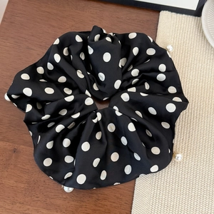 Detail of satin polka dot scrunchie with pearl edge on rustic wooden table background