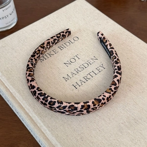 Detail view of handmade leopard print velvet headband resting on a book background
