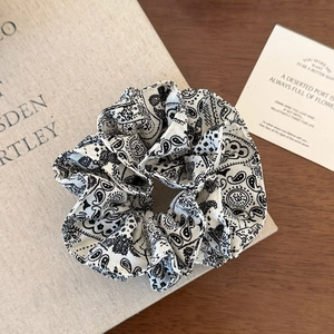Detailed view of paisley pattern on a white and black cotton fabric hair scrunchie