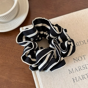 Detail of black and white striped pleated scrunchie with soft chiffon fabric texture