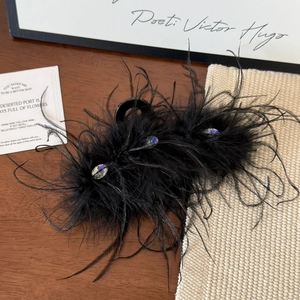 Macro detail of ostrich feather hair claw clip with colorful sparkling gemstones in black