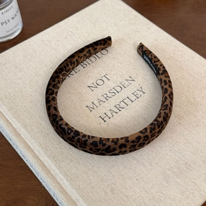 Detailed view of the handmade leopard print velvet headband resting on a book