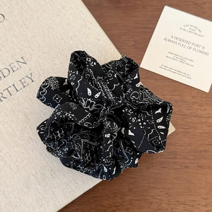 Macro detail of black and white paisley bandana print fabric scrunchie with soft pleats