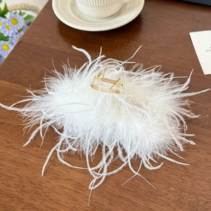 Détail d'une grande pince à cheveux ambre ornée de plumes blanches douces sur bois