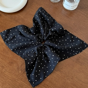 Λεπτομερής προβολή μαύρου scrunchie με λευκά καρδιές σε μαλακό ύφασμα με πτυχώσεις