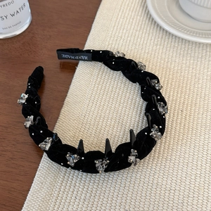 Detalle de diadema de terciopelo negro con cristales, tachuelas y etiqueta Hand Made