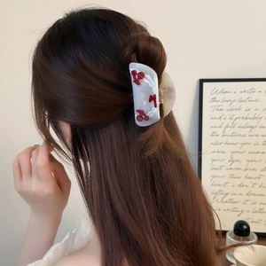 Elegant pearl white acetate hair claw clip with red cherry accents on a model
