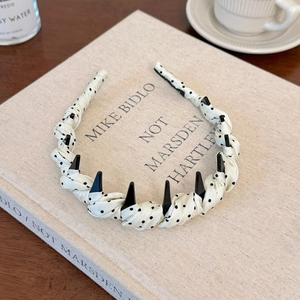 Detailed view of beige polka dot headband with black spikes on a vintage book