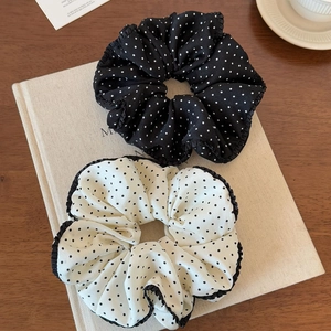 Close-up of black and white polka dot scrunchies with wavy edges on a textured book