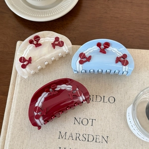 Three acetate cherry hair claws in white, blue, and red with scalloped wave edges