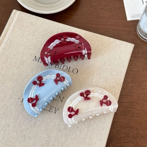 Detailed macro view of three oversized acetate hair claws with 3D cherry patterns