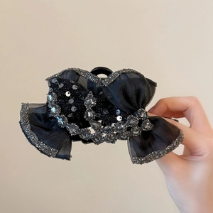 Détail de la pince à cheveux noeud en tulle noir ornée de strass brillants et de paillettes