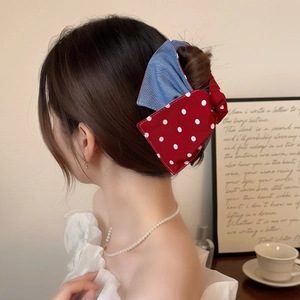 Polka dot red and denim blue bow hair claw clip worn on model with vintage decor