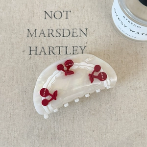 Detail shot of pearl white acetate hair claw clip with red cherry rhinestone motifs
