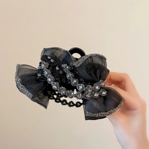 Détail de la pince à cheveux avec nœud en strass, tissu organza noir et éclats argentés