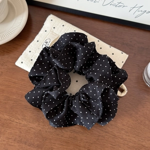 Detail of black polka dot fabric scrunchie on a cozy desk with warm lighting