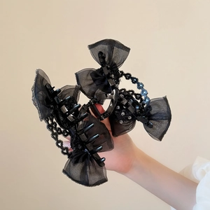 Détail de la pince à cheveux avec nœud en dentelle noire, paillettes et perles chic