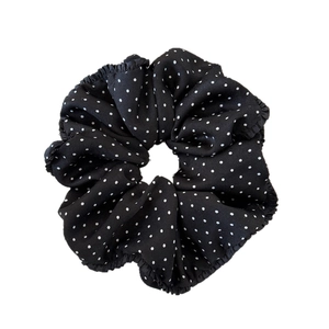 Elegant black scrunchie with white polka dots and ruffled edges for women's ponytail