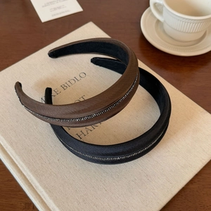 Set di cerchietti con strass marroni e neri su libro per acconciature eleganti retrò