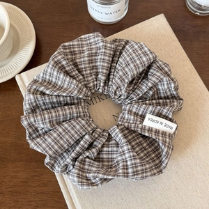 Detail eines grau-weiß karierten Stoff-Haargummis mit einem Made in Korea Seitenlabel