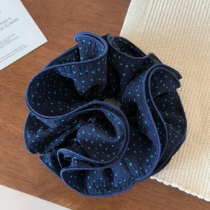Detail of navy blue polka dot scrunchie with layered chiffon fabric on wooden surface