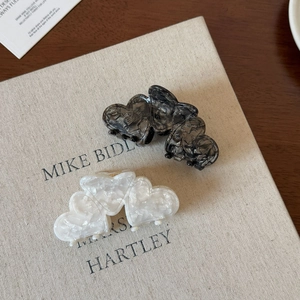 Detail of marble and pearl acetate heart hair claws on a book for hair styling