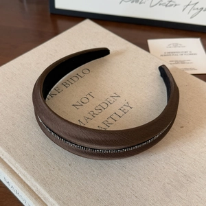 Dettaglio del cerchietto imbottito marrone scuro con eleganti decorazioni di cristalli