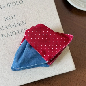 Macro detail of triangle hair claw featuring red polka dots and blue denim fabric texture