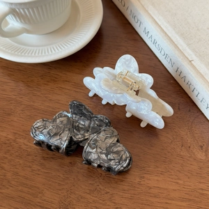 Elegant acetate butterfly hair clips in pearl white and marble grey on a wooden desk