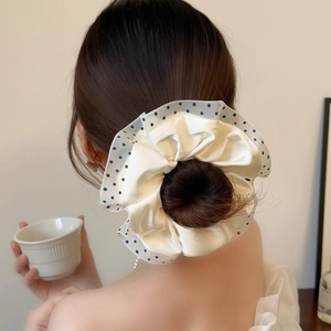Back view of a bun hairstyle secured with a cream satin and polka dot mesh scrunchie
