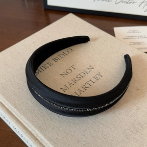 Primo piano di un cerchietto vintage nero con strass argentati lucidi su un libro
