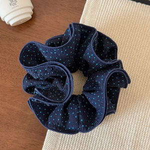 Detailed view of dark blue polka dot scrunchie on wood and woven background