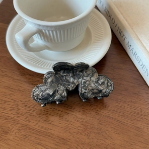 Detailed view of heart-shaped marble textured hair claw clip on vintage wooden desk