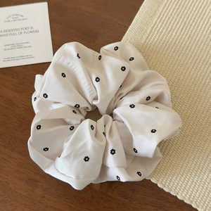 Primo piano di un elastico per capelli in raso beige a fiori su un tavolo di legno