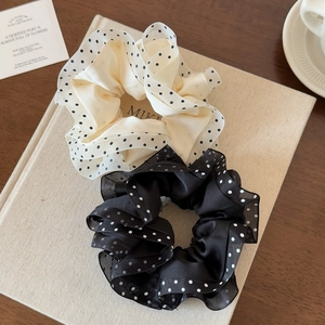 Elegant polka dot mesh scrunchies in black and white set on a textured book surface