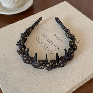 Detail of black fabric headband with gold dots, metallic spikes and crystal accents