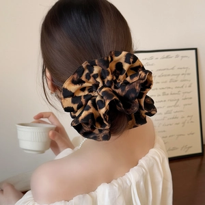 Fashionable leopard print oversized hair scrunchie with silky texture worn by a model