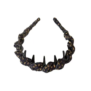 Leopard print headband with black spikes and small rhinestones on a white background