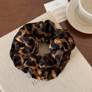 Close-up of leopard print satin scrunchie on vintage books and art cards for hair styling