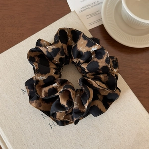 Detailed view of leopard print satin scrunchie with elegant black stitched edges