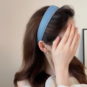 Detailed view of blue denim headband with orange double stitching on model