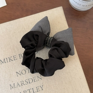 Elegant grey bow scrunchie with handmade detail on vintage book background