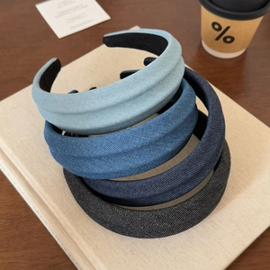 Detail view of four thickened denim fabric headbands in a gradient of blue and black shades