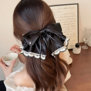 Elegant black satin hair clip with white lace trim and rhinestones in a lifestyle setting