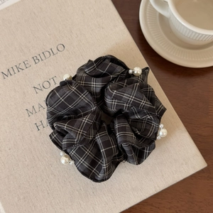 Detail of vintage checkered hair scrunchie with white pearls on a minimalist background