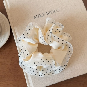 Detail of elegant cream satin scrunchie with black polka dots and mesh lace trim decor