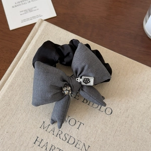 Detailed shot of grey bow scrunchie with sparkling rhinestone and silver perfume pendant