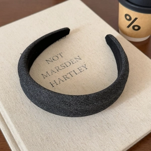Detailed texture of black denim fabric headband resting on a linen book cover