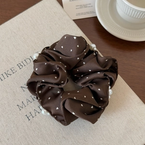 Détail d'un chouchou en satin marron foncé avec pois cœurs blancs et perles décoratives
